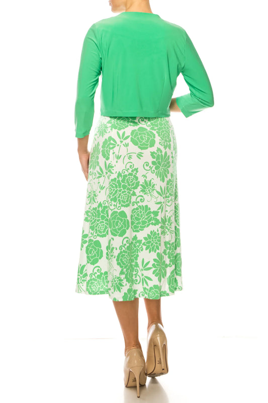 Woman wearing a green bolero jacket and a green and white floral midi skirt.