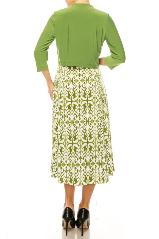 Back view of a woman wearing a green cropped jacket and a green and white patterned midi skirt.