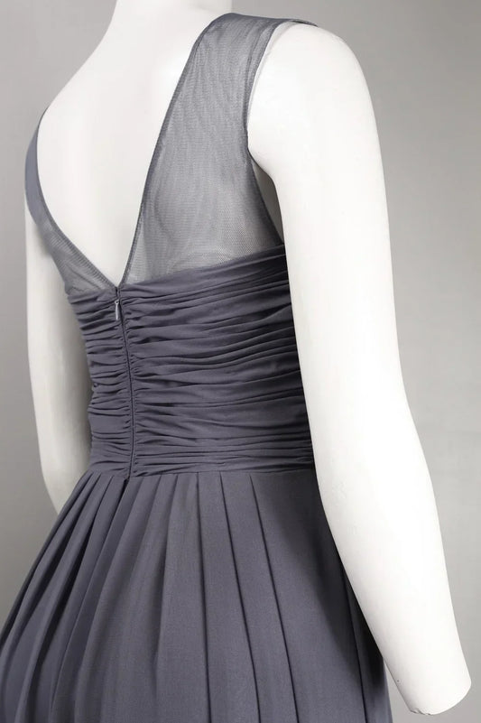Back view of a charcoal grey evening gown with a sheer mesh bodice and pleated skirt.