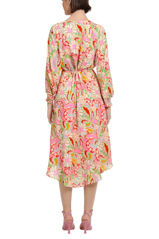 Back view of a woman wearing a colorful floral print midi dress and pink heels.