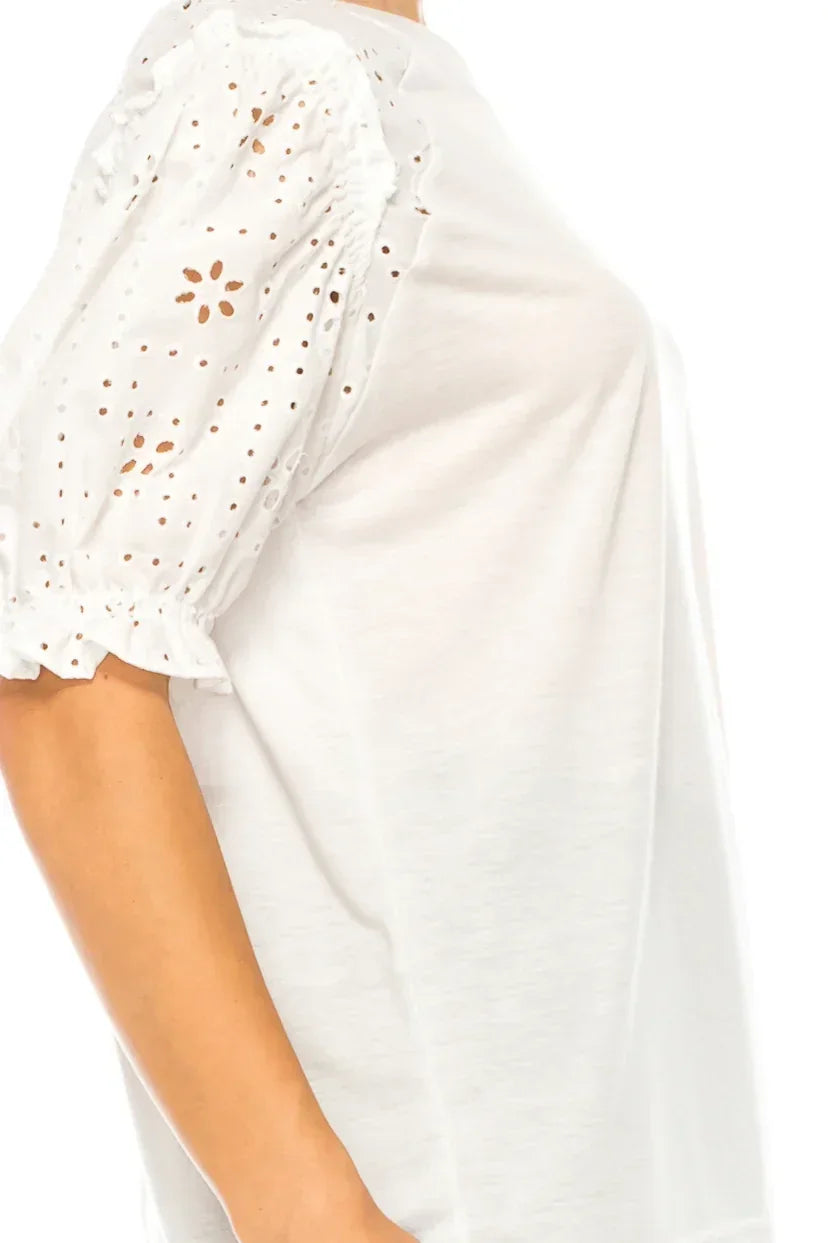 Close-up of a white women's blouse with eyelet embroidery on the puff sleeve.