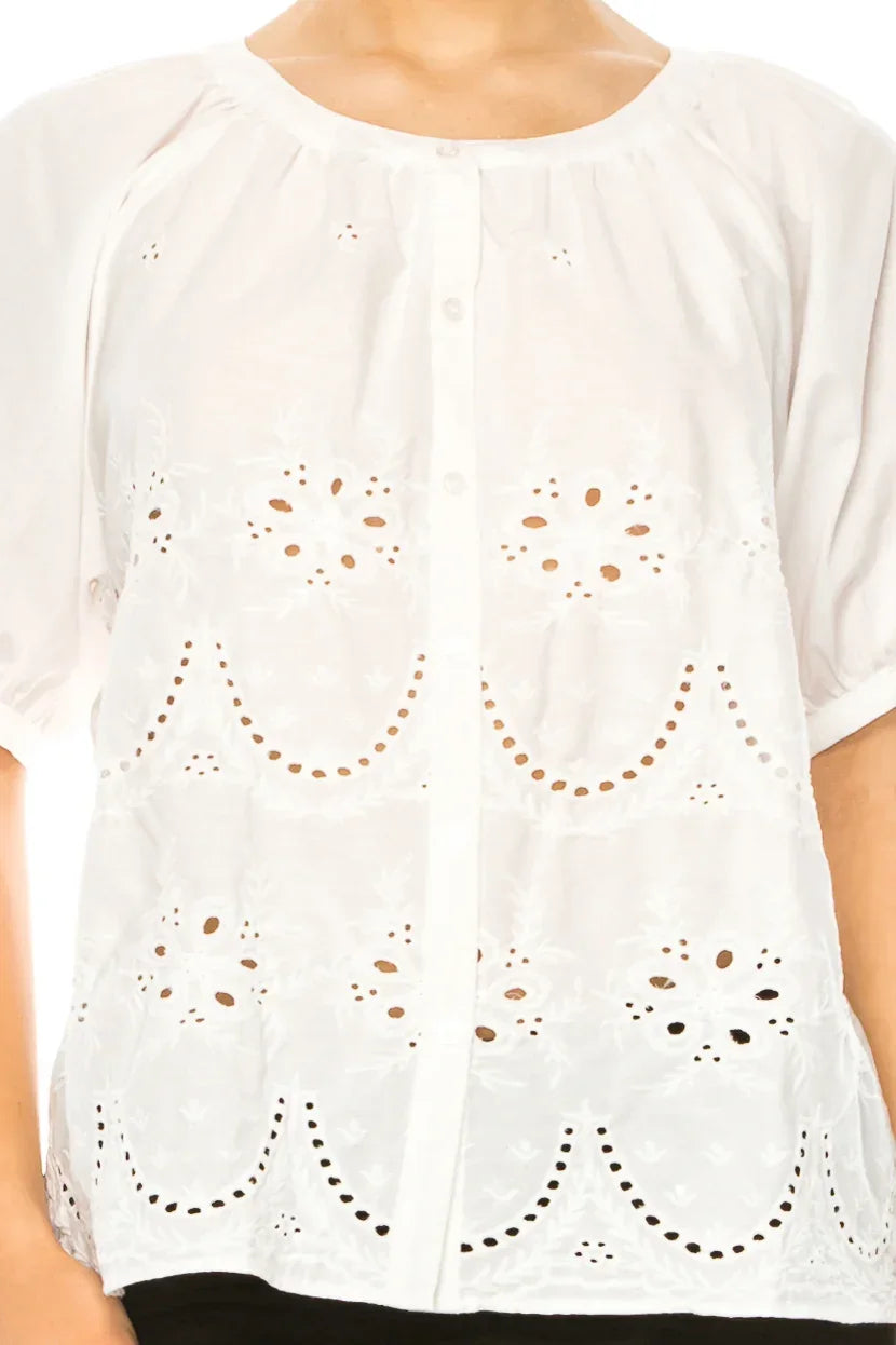 Woman wearing a white short-sleeve button-down blouse with intricate eyelet embroidery details.