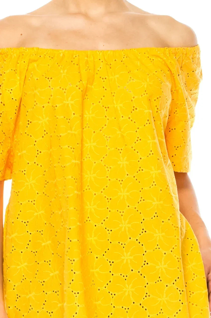 Woman wearing a bright yellow off-the-shoulder eyelet lace dress.