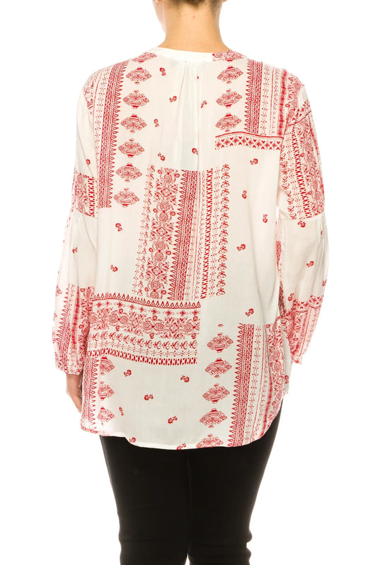 Back view of a woman wearing a white blouse with red bohemian prints and black pants.