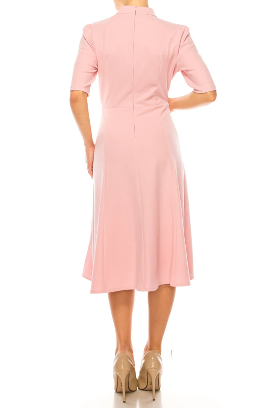 Rear view of a woman wearing a short-sleeve, midi-length pink evening dress and beige heels.