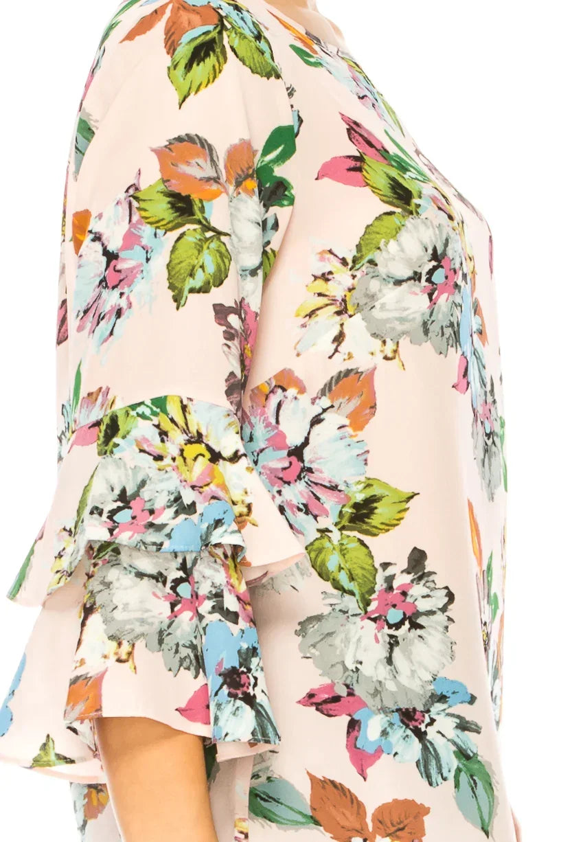 Close-up of a light pink women's blouse with colorful floral print and ruffled sleeves.