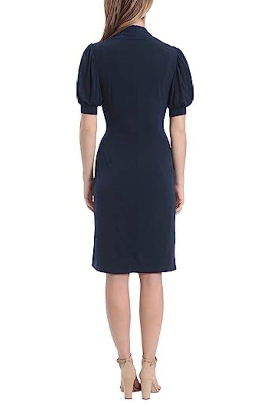 Back view of a woman wearing a navy blue knee-length dress with puff sleeves and nude heels.