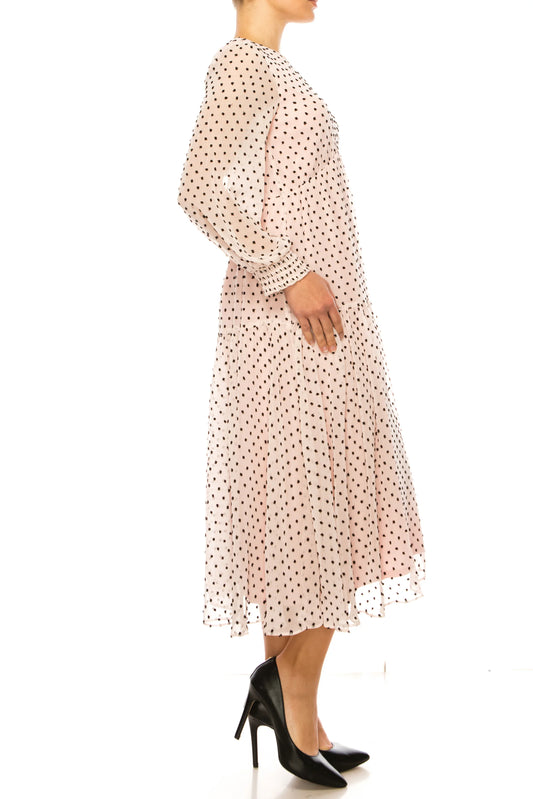 Woman wearing an elegant light pink polka dot midi dress and black high heels.