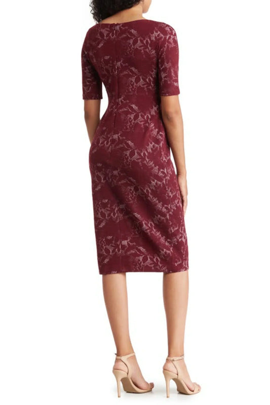 Back view of a woman wearing a burgundy floral lace sheath dress and nude heels.
