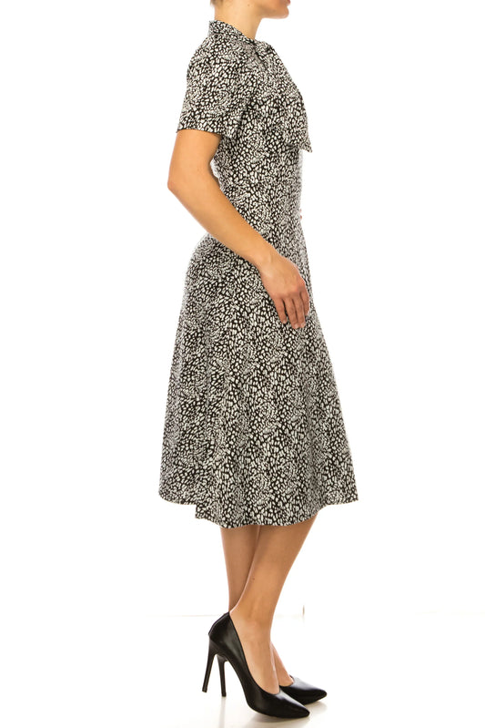 Woman wearing a black and white leopard print midi dress and black high heels.