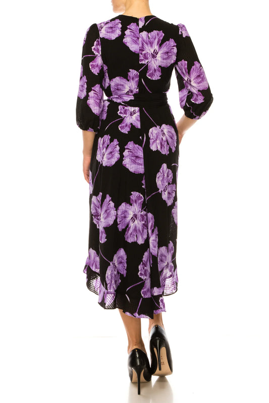 Back view of a woman wearing a black midi dress with large purple floral prints.