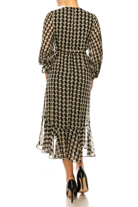 Back view of a woman in a black and white houndstooth midi dress with ruffled hem.