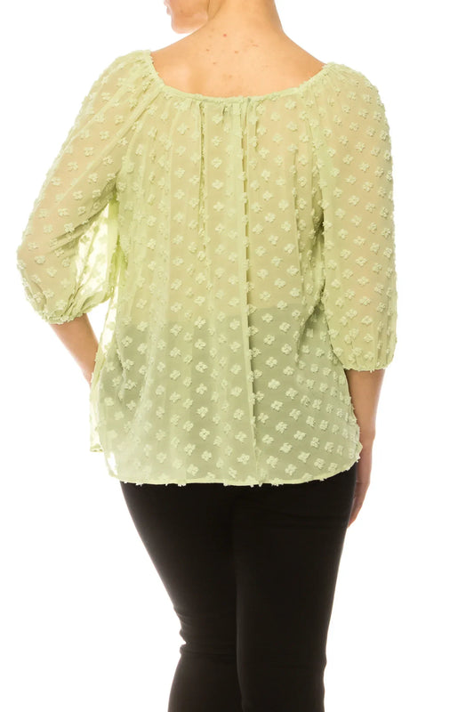 Back view of a woman wearing a light green textured blouse with black pants