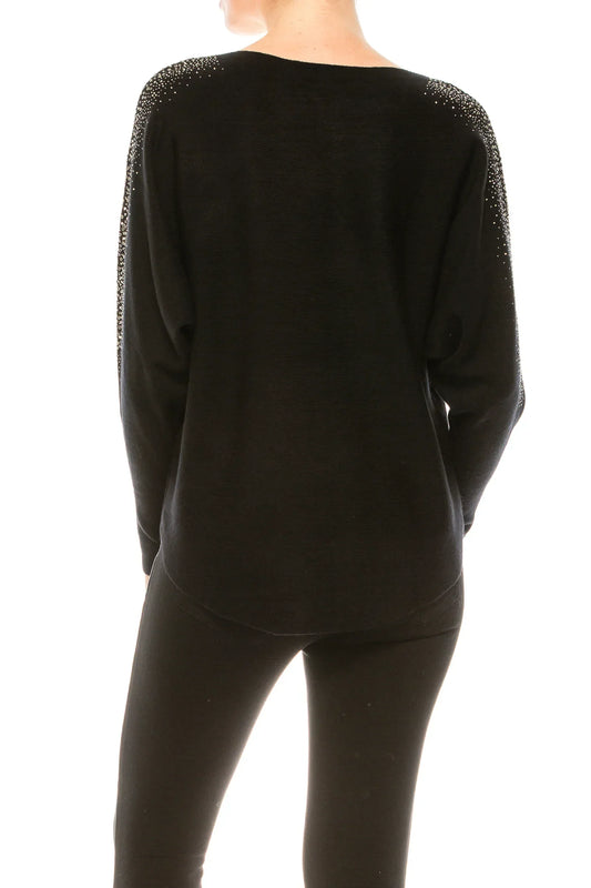 Back view of a woman wearing a black long-sleeve sweater with rhinestone shoulder details.