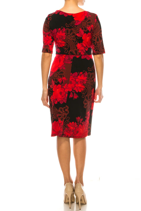 Back view of a woman wearing a black and red floral print knee-length dress and nude heels.
