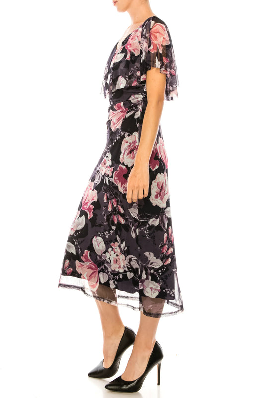 Woman wearing an elegant navy floral midi dress with sheer sleeves and black pumps.