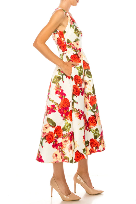 Woman wearing an elegant white A-line dress with a red floral print and beige heels.