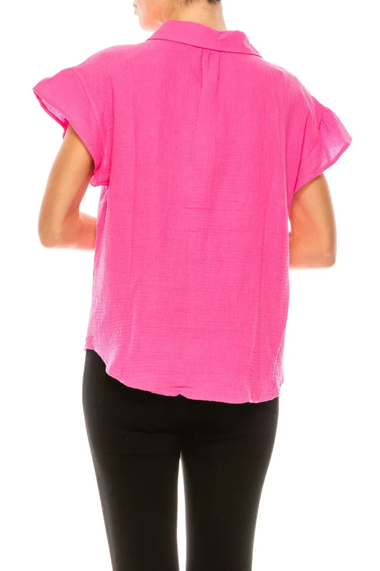 Back view of a woman wearing a bright pink short-sleeved button-down blouse and black pants.