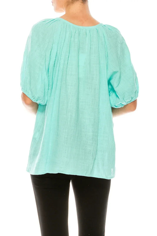 Back view of a woman wearing a mint green puff sleeve blouse and black pants