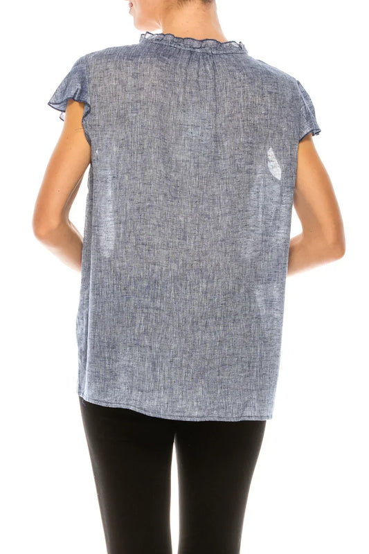 Back view of a woman wearing a blue linen short-sleeve blouse with a ruffled collar.