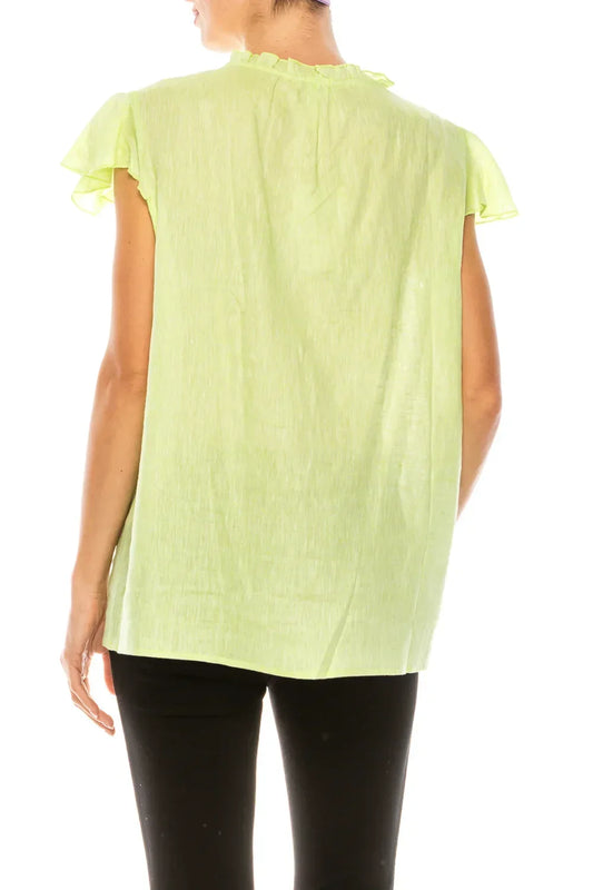 Back view of a woman wearing a lime green short-sleeve ruffled linen blouse and black pants.