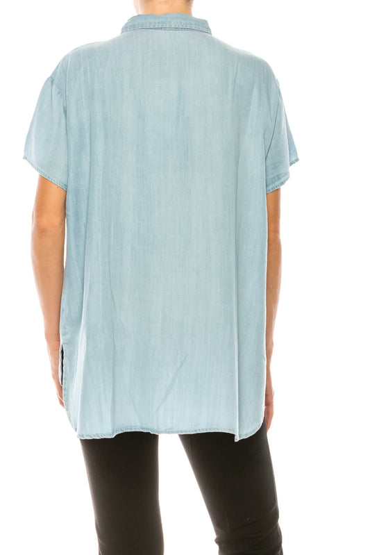 Back view of a woman wearing a light blue short-sleeve button-down shirt and black pants.