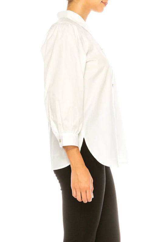 Side view of a woman wearing a white button-down blouse with puff sleeves and black pants.
