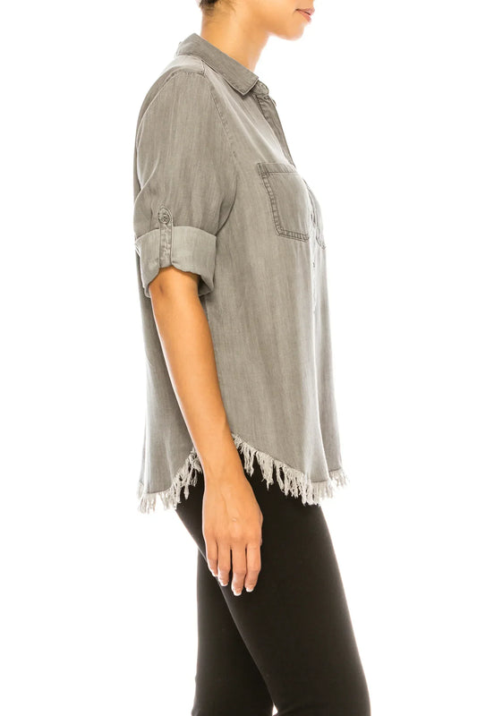 Side view of a woman wearing a grey button-down shirt with frayed hem and black pants.