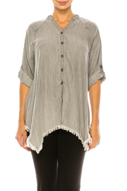 Woman wearing a grey button-down tunic with frayed hem and rolled sleeves.
