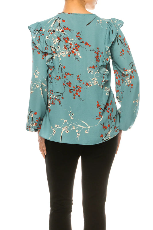 Back view of a woman wearing a teal floral print blouse with ruffle shoulder details.