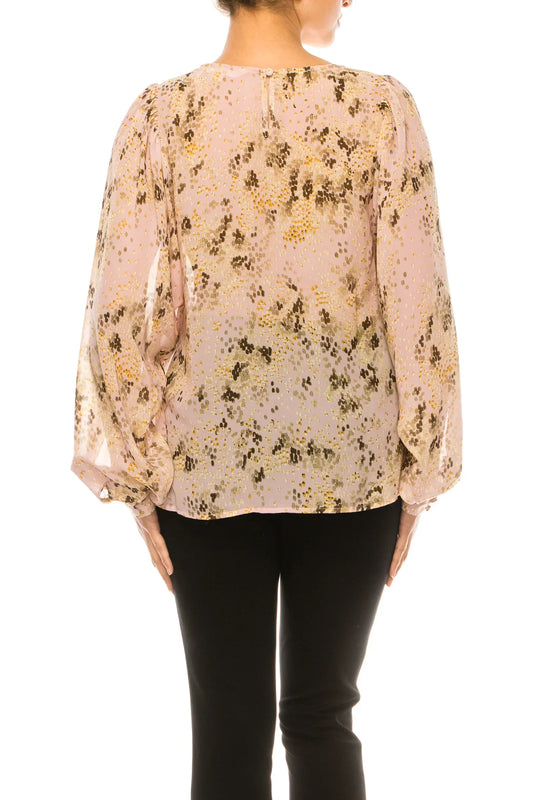 Back view of a woman wearing a pink floral print blouse with balloon sleeves and black pants.