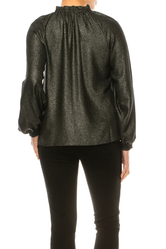 Back view of a woman wearing a shimmering black long-sleeve blouse and black trousers.