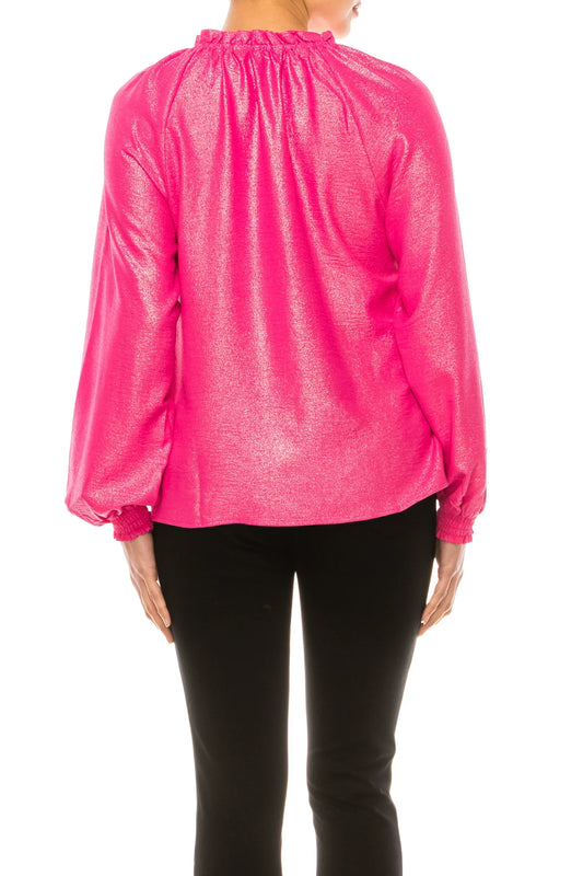 Back view of a woman wearing a shimmering hot pink metallic long-sleeve blouse and black pants.