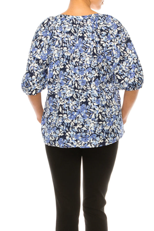 Back view of a woman wearing a blue and white floral print blouse and black pants.