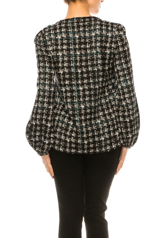 Back view of a woman wearing a black and white plaid tweed jacket and black trousers.