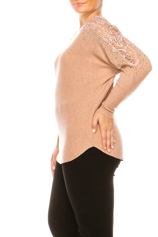 Woman wearing a beige long-sleeve top with lace shoulder detail and black trousers