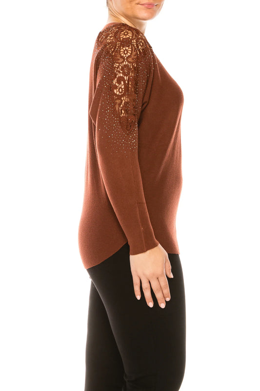 Woman in a brown long-sleeve top with lace and rhinestone shoulder details and black pants.