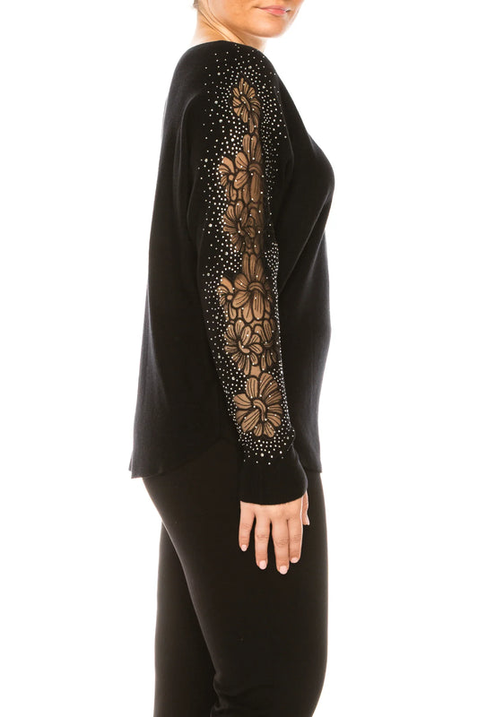 Woman wearing a black long-sleeve top with floral lace and rhinestone sleeve detail.