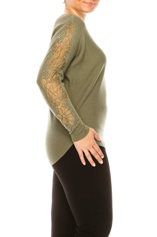Woman wearing an olive green long sleeve top with floral lace and rhinestone sleeve details.