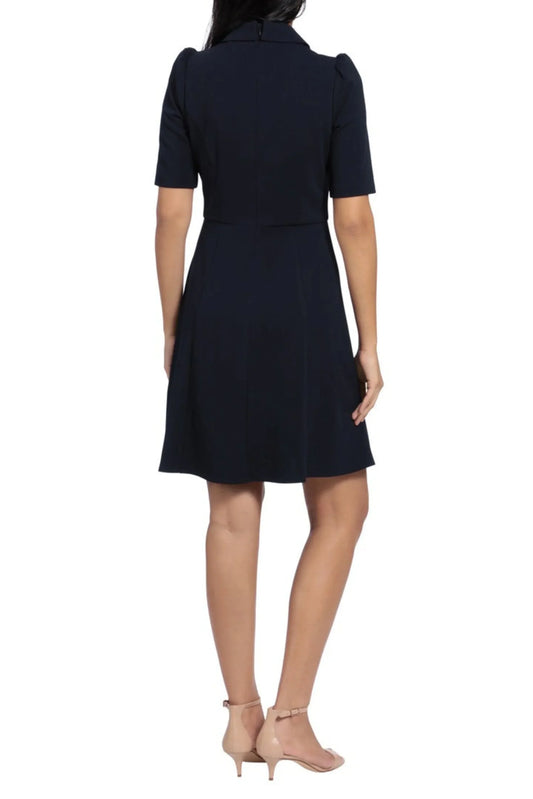 Back view of a woman wearing a navy blue short-sleeved dress and beige heels.
