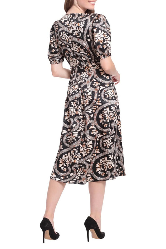 Woman wearing a black and beige paisley print midi dress with puff sleeves and black heels.