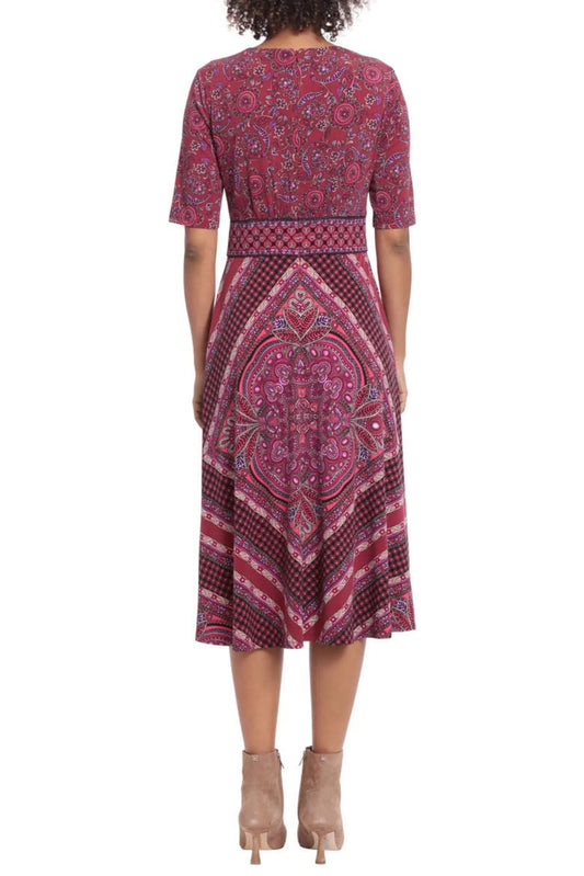 Back view of a woman wearing a red and purple paisley print midi dress with ankle boots