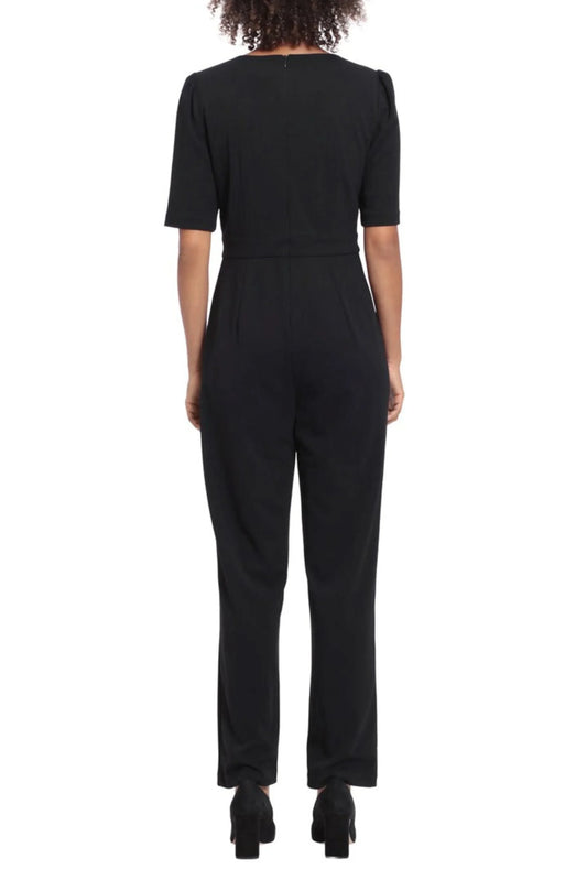 Back view of a woman wearing a short-sleeved black elegant jumpsuit and black heels.