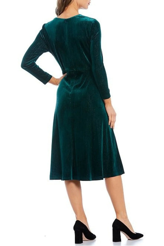 Back view of a woman wearing an elegant emerald green velvet midi dress and black heels.