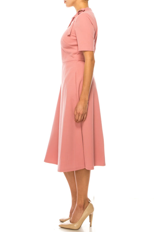 Woman wearing an elegant pink short-sleeve midi dress and beige heels.