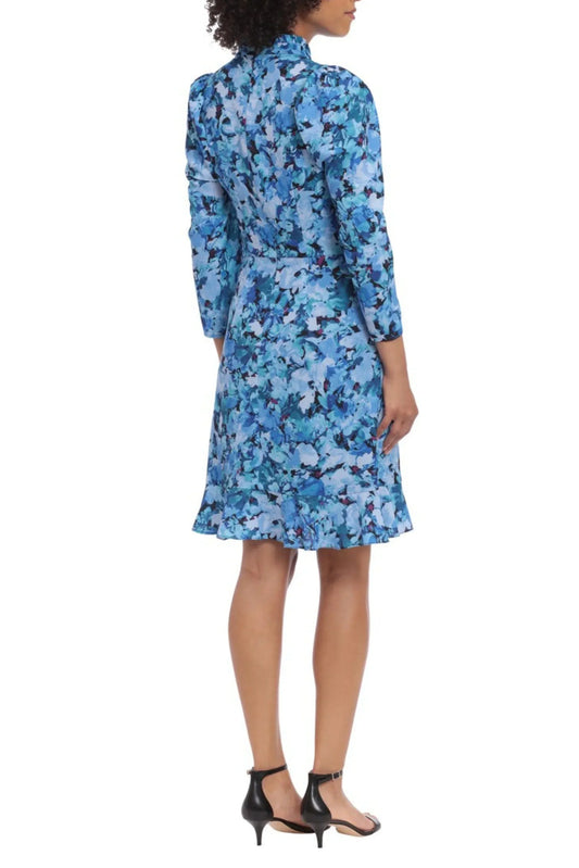 Back view of a woman wearing a blue floral print midi dress and black heels.
