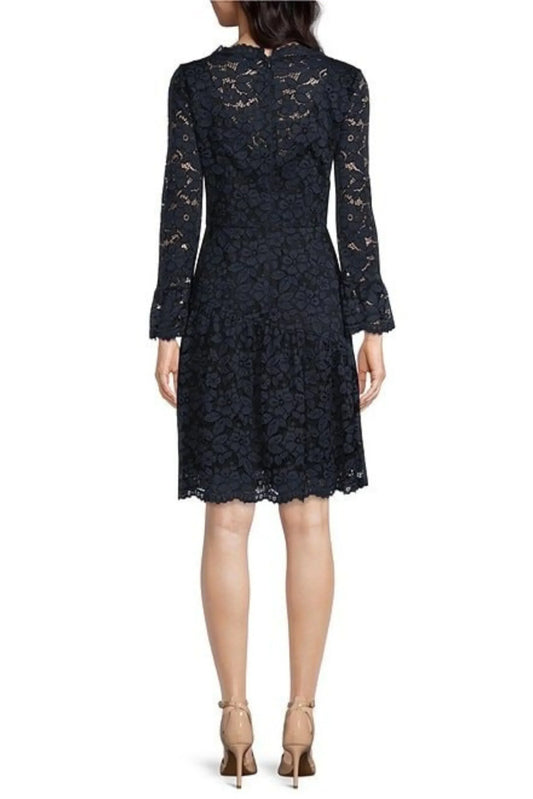 Back view of a woman wearing a navy blue floral lace dress with bell sleeves and beige heels.