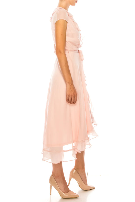 Woman wearing an elegant light pink ruffle midi dress and nude pumps