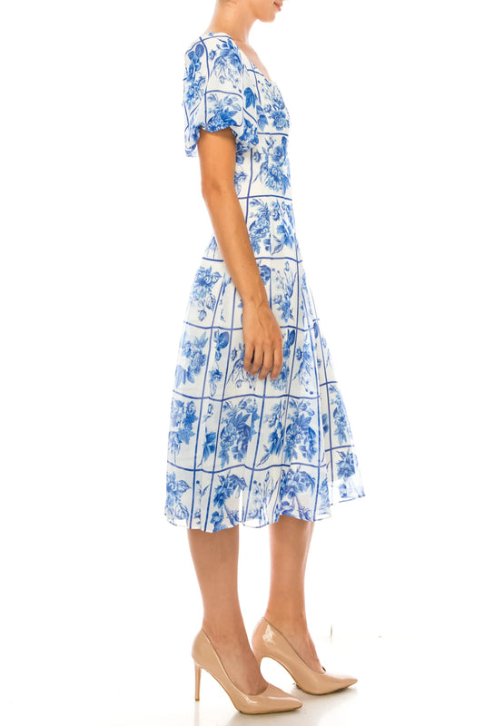 Woman wearing a white and blue floral print midi dress with nude pumps
