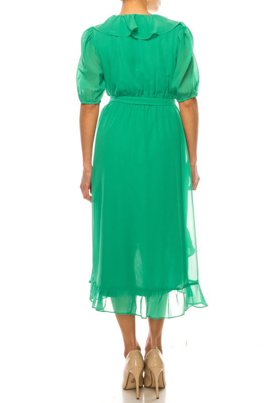 Back view of a woman wearing an elegant green midi dress with ruffle details and beige heels.